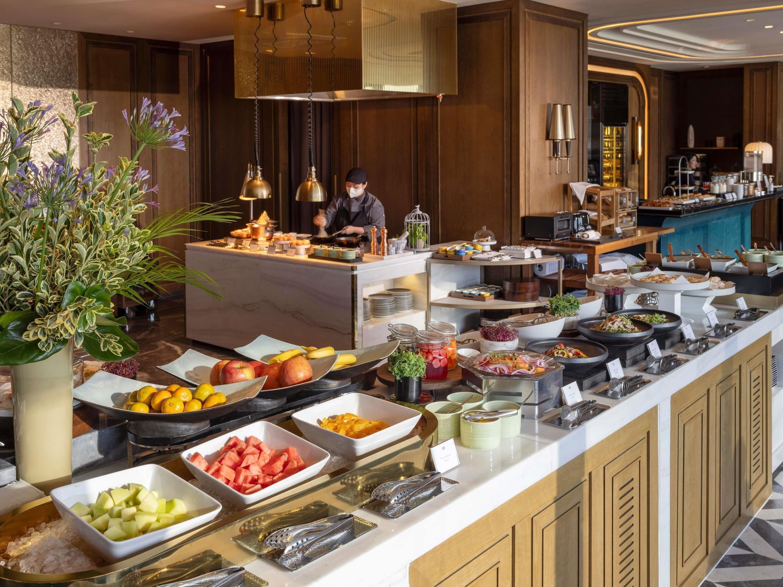 Een ontbijtbuffet met diverse gerechten, een kok in de weer en een verzorgd interieur.
