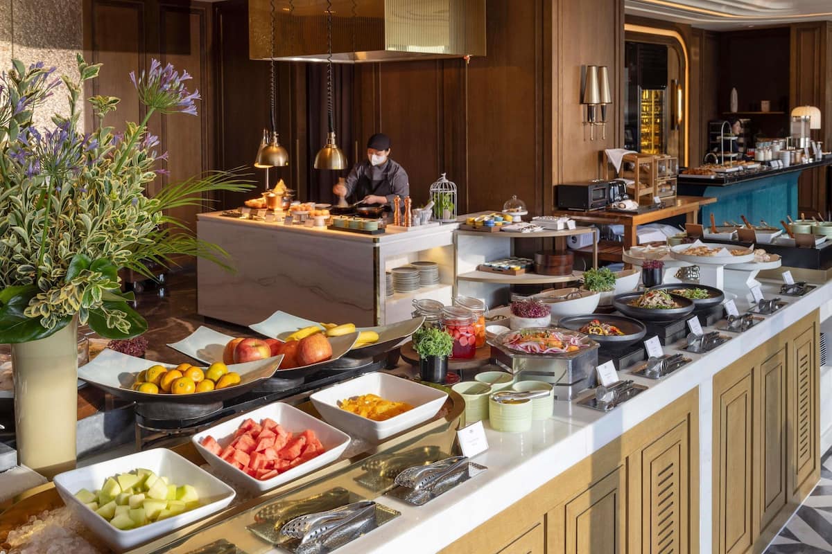 A buffet with various food items, a chef preparing food, and a well-lit interior.