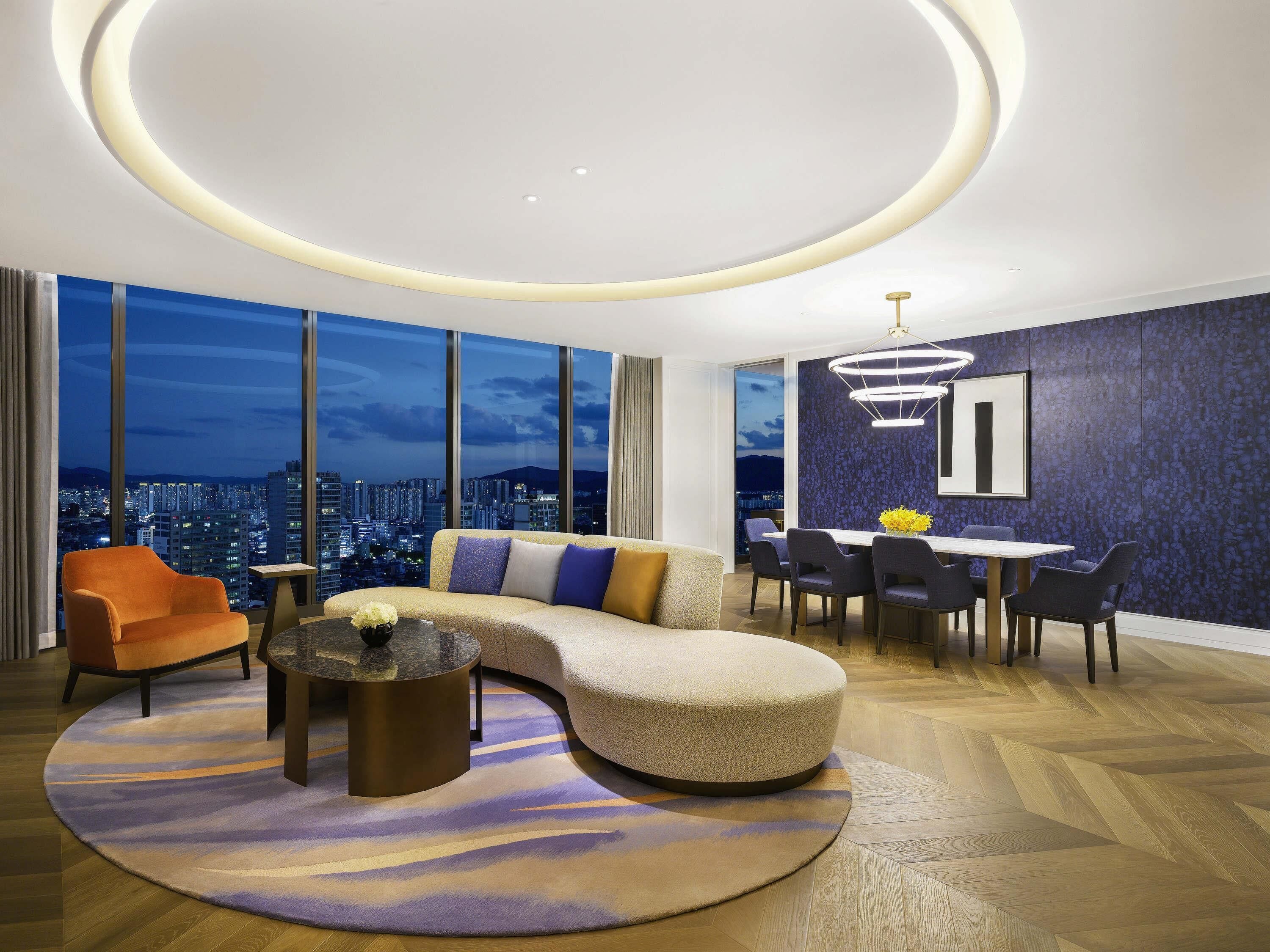 A modern living room with a curved sofa, a dining table, and chairs.