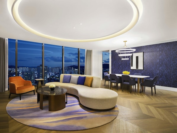 A modern living room with a curved sofa, a dining table, and chairs.