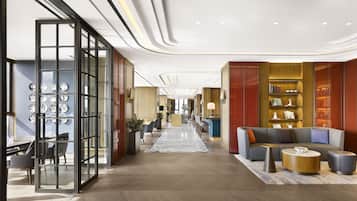 Una hall d'hotel moderna con un'area salotto centrale, una reception e un divisorio in vetro decorato con piatti.
