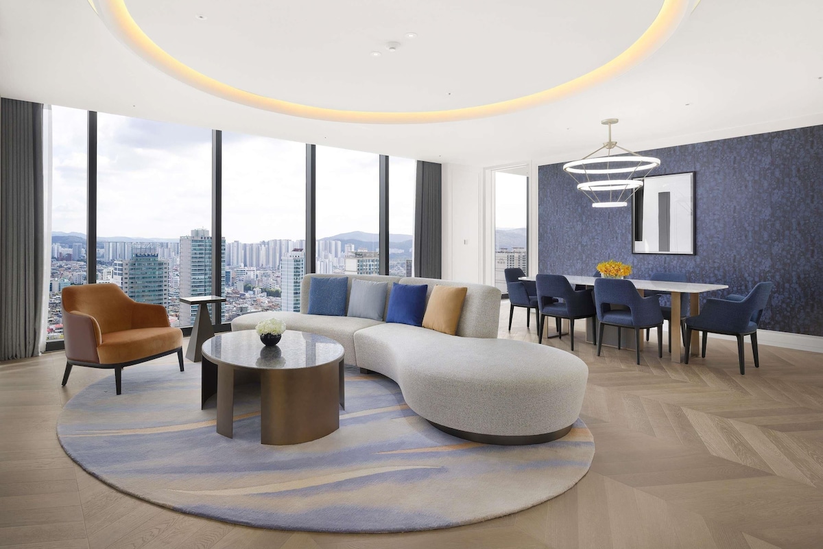 A modern living room with a sofa, chairs, a coffee table, and a dining area with a table and chairs.
