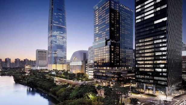 A cityscape with modern high-rise buildings, a river, and a park area.