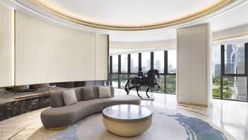 A modern living room with a sectional sofa, a round coffee table, and a city view through large windows.