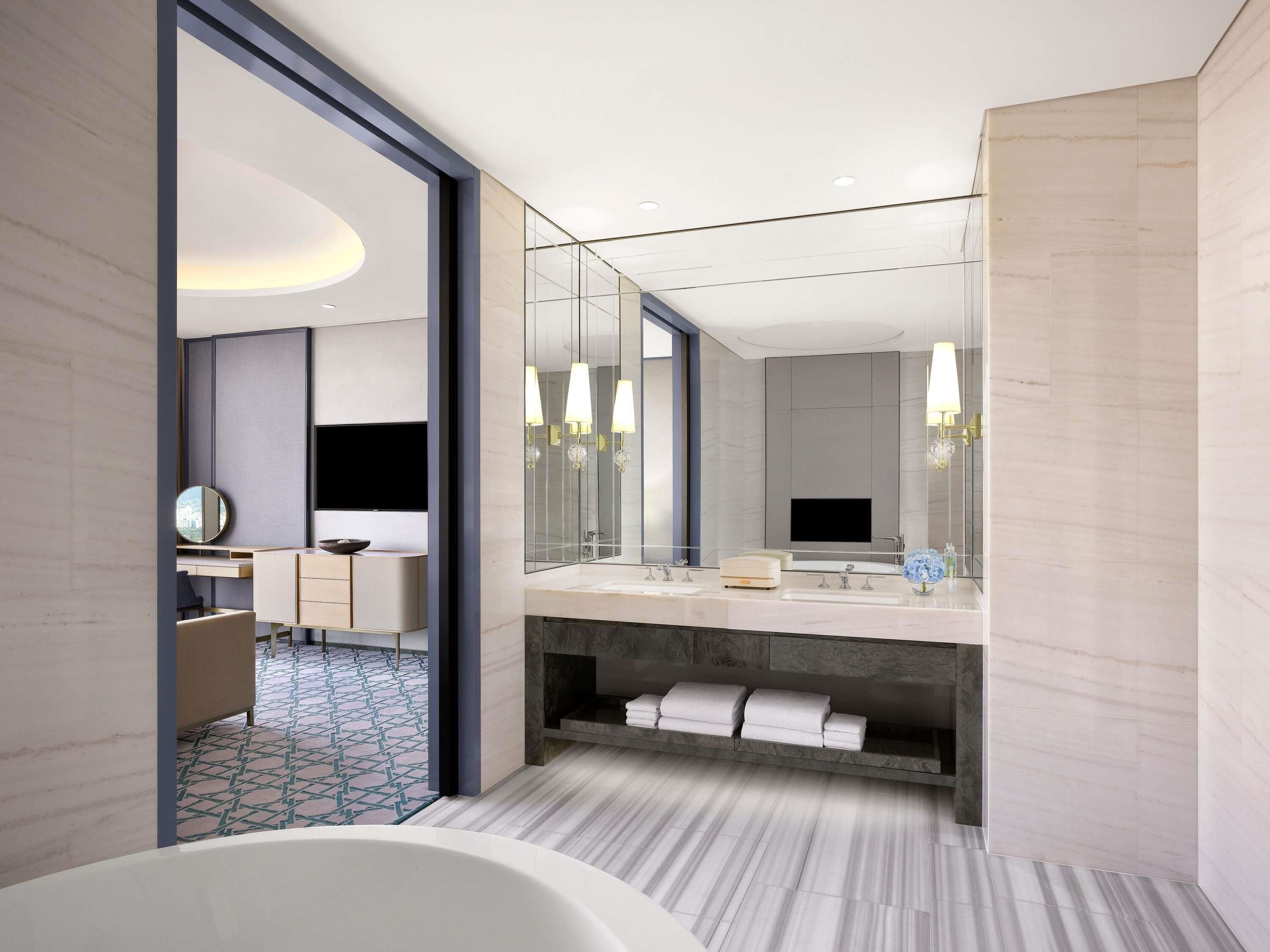 A modern bathroom with a large mirror, a bathtub, and a vanity with a sink.