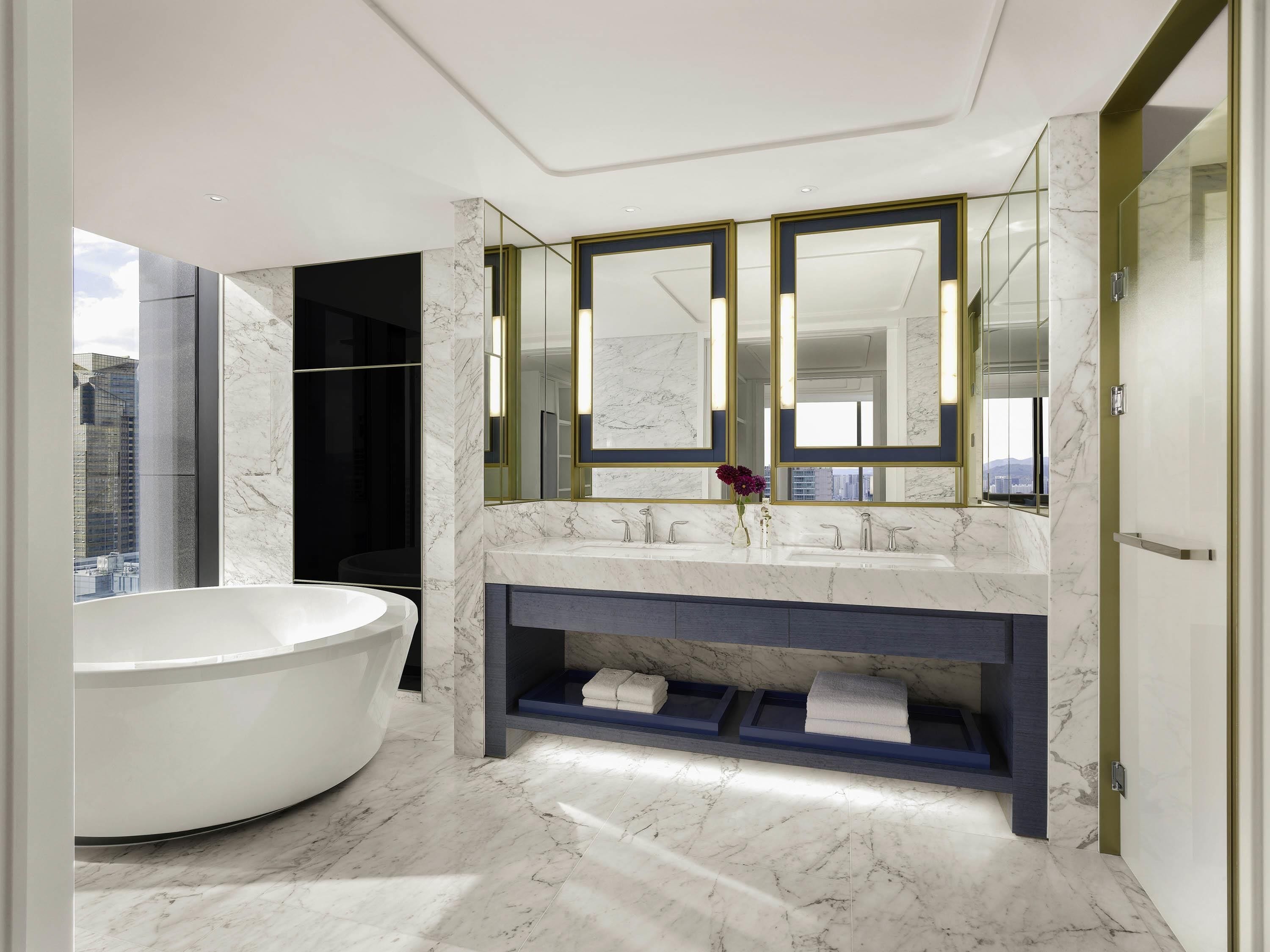 A modern bathroom with a freestanding bathtub, a vanity with dual sinks, and a large mirror.