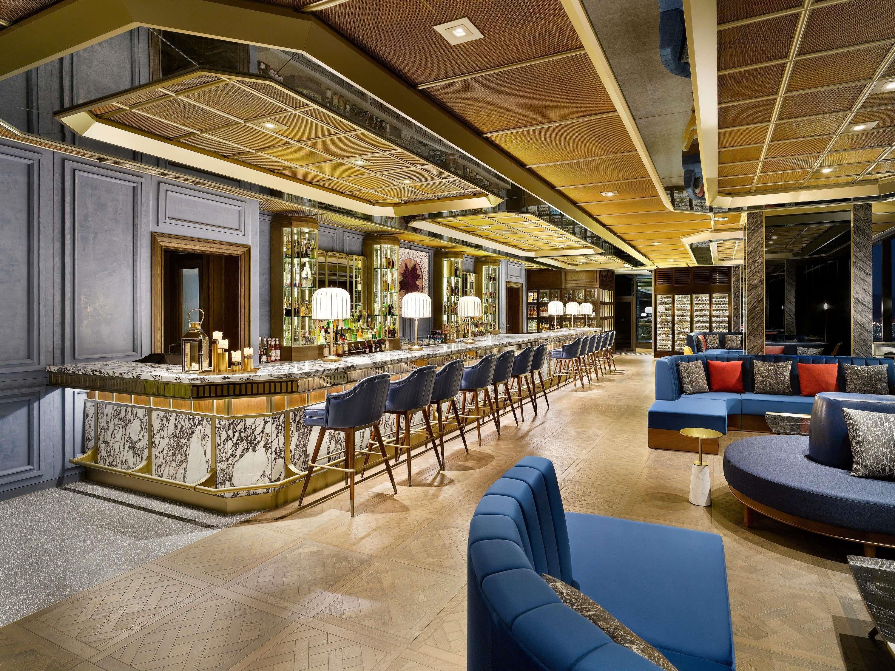 A bar area with a marble countertop, bar stools, and a seating area with sofas and chairs.