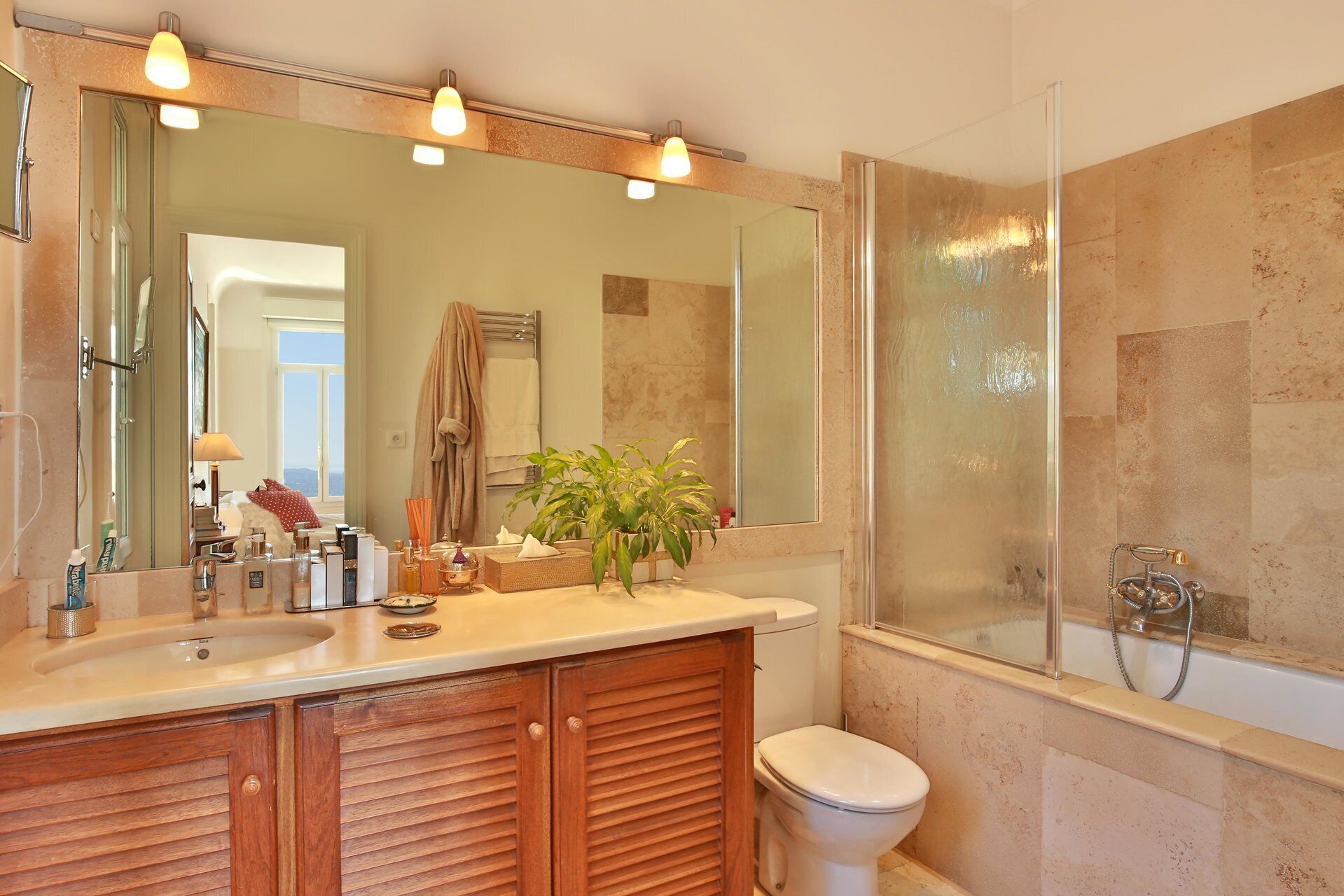 A bathroom with a double sink vanity, a large mirror, a shower, and a toilet.