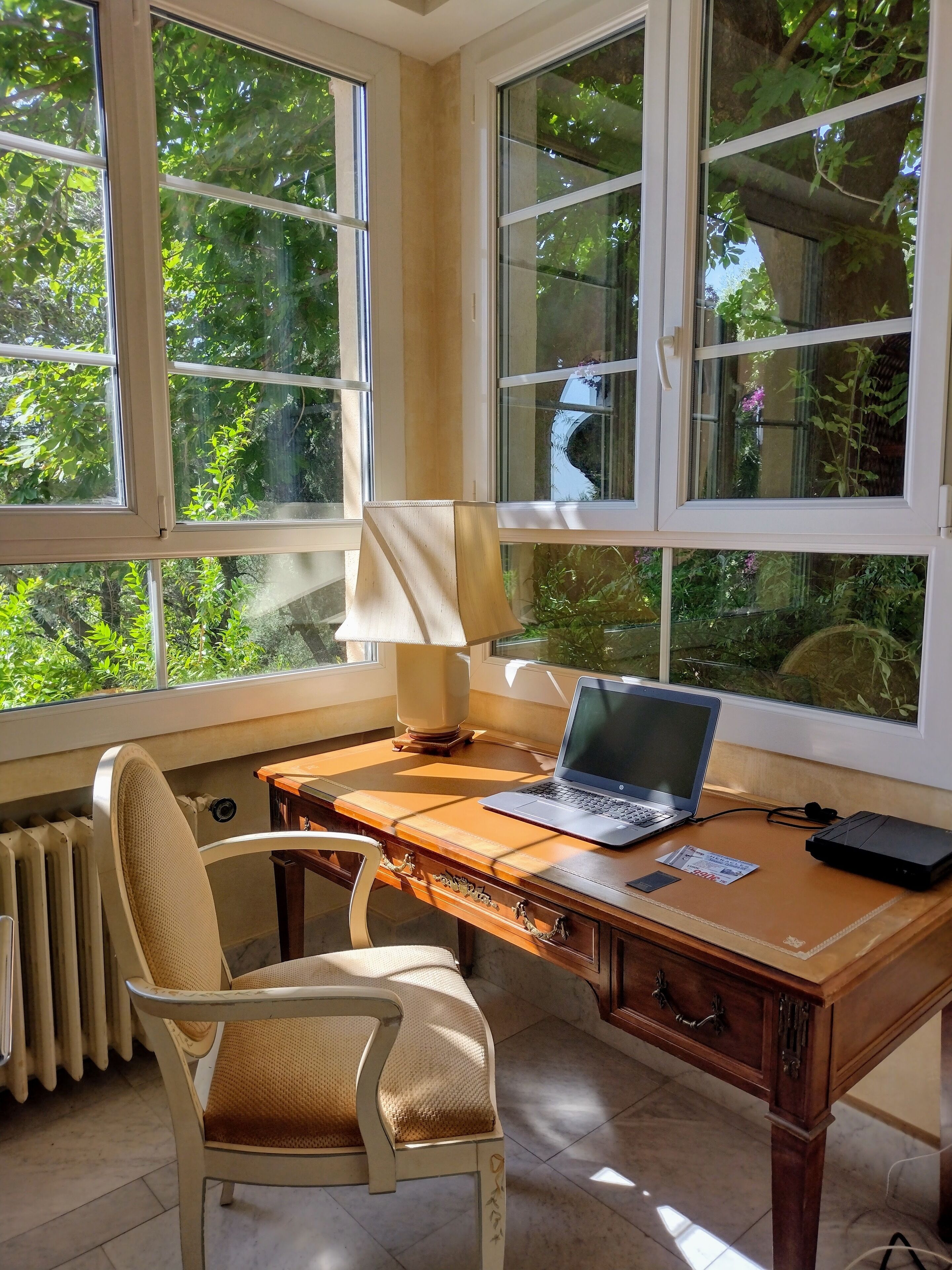 A room with a wooden desk, a laptop, a lamp, and a chair.