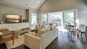 A spacious living room with a large TV, comfortable seating, and a balcony with outdoor furniture. - 13 Starboard Tack - Beautiful oasis w/ private dock & Pool - Sleeps up to 17 (Hilton Head Island)