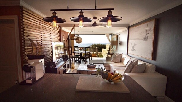 A modern living room with a white sofa, a dining table with chairs, and a kitchen area with a coffee machine. - 4 Dolphin views La Mercy (La Mercy)
