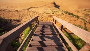 A wooden staircase leading to a beach with waves in the background. - 4 Dolphin views La Mercy (La Mercy)