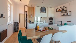 A modern kitchen with a wooden dining table, white chairs, and a central island. - ALTAYA • Apt with balcony and sea view in Biarritz (Biarritz)