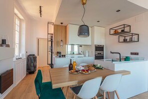 Eine moderne Küche mit Holztisch, weißen Stühlen und einer zentralen Kochinsel.