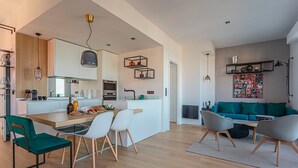 A modern kitchen with a central island, dining area with chairs, and a living room with a sofa and a coffee table. - ALTAYA • Apt with balcony and sea view in Biarritz (Biarritz)
