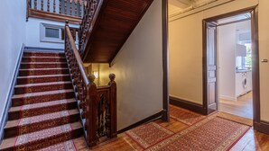 Un escalier avec une rampe en bois et des marches recouvertes de moquette, menant à l’étage supérieur.