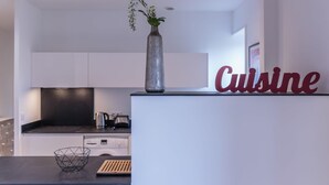 Une cuisine moderne avec des meubles blancs, un plan de travail noir, un vase de fleurs et une enseigne indiquant « Cuisine ».