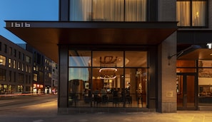 A modern building with a large glass facade, a wooden overhang, and a visible address number.