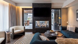 A modern living room with a fireplace, comfortable seating, and a large window offering a view of the city. - Thompson Denver, by Hyatt (Denver)