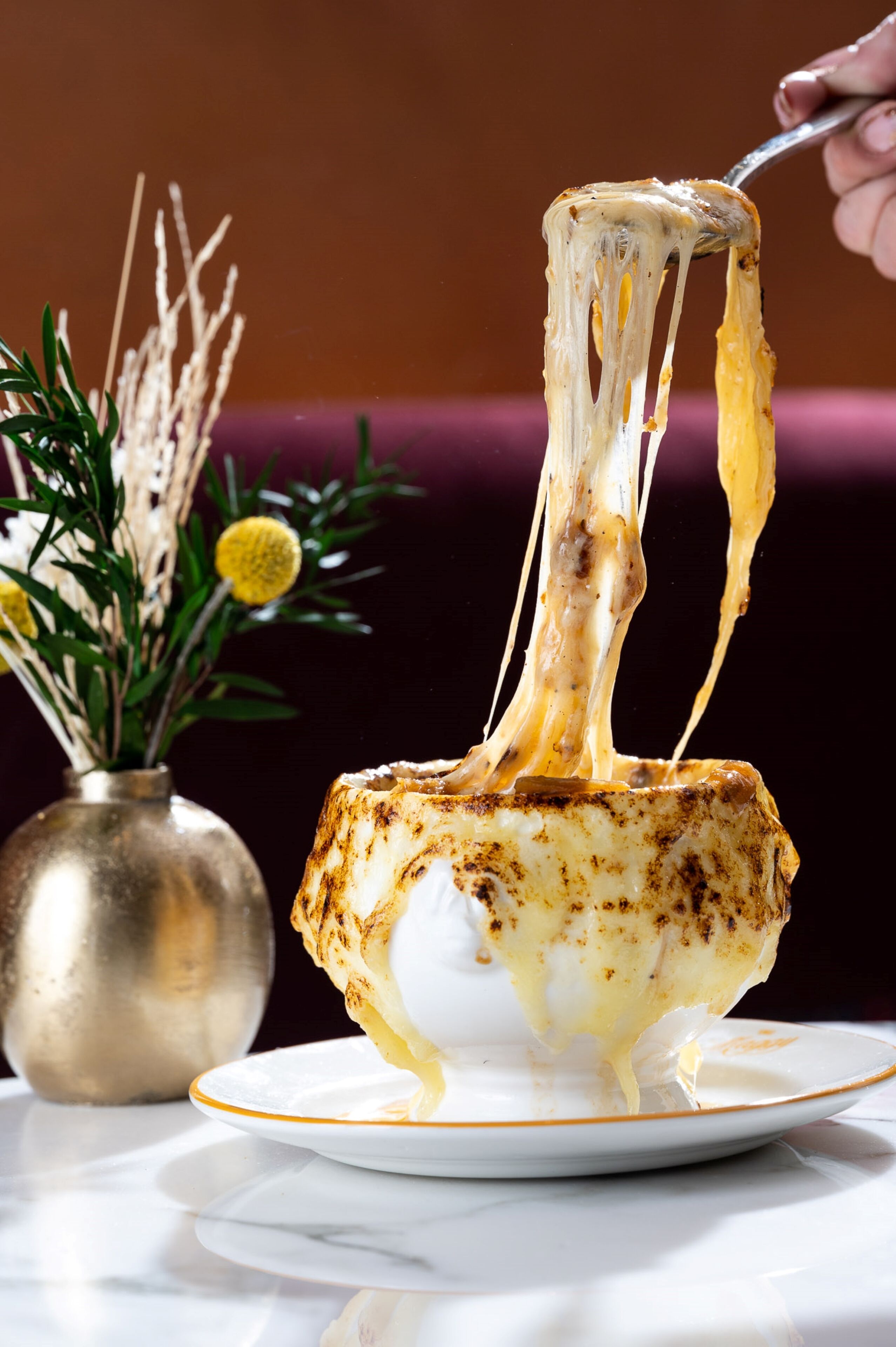 A dessert with melted cheese being lifted by a fork.