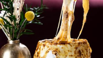 A dessert with melted cheese being lifted by a fork.
