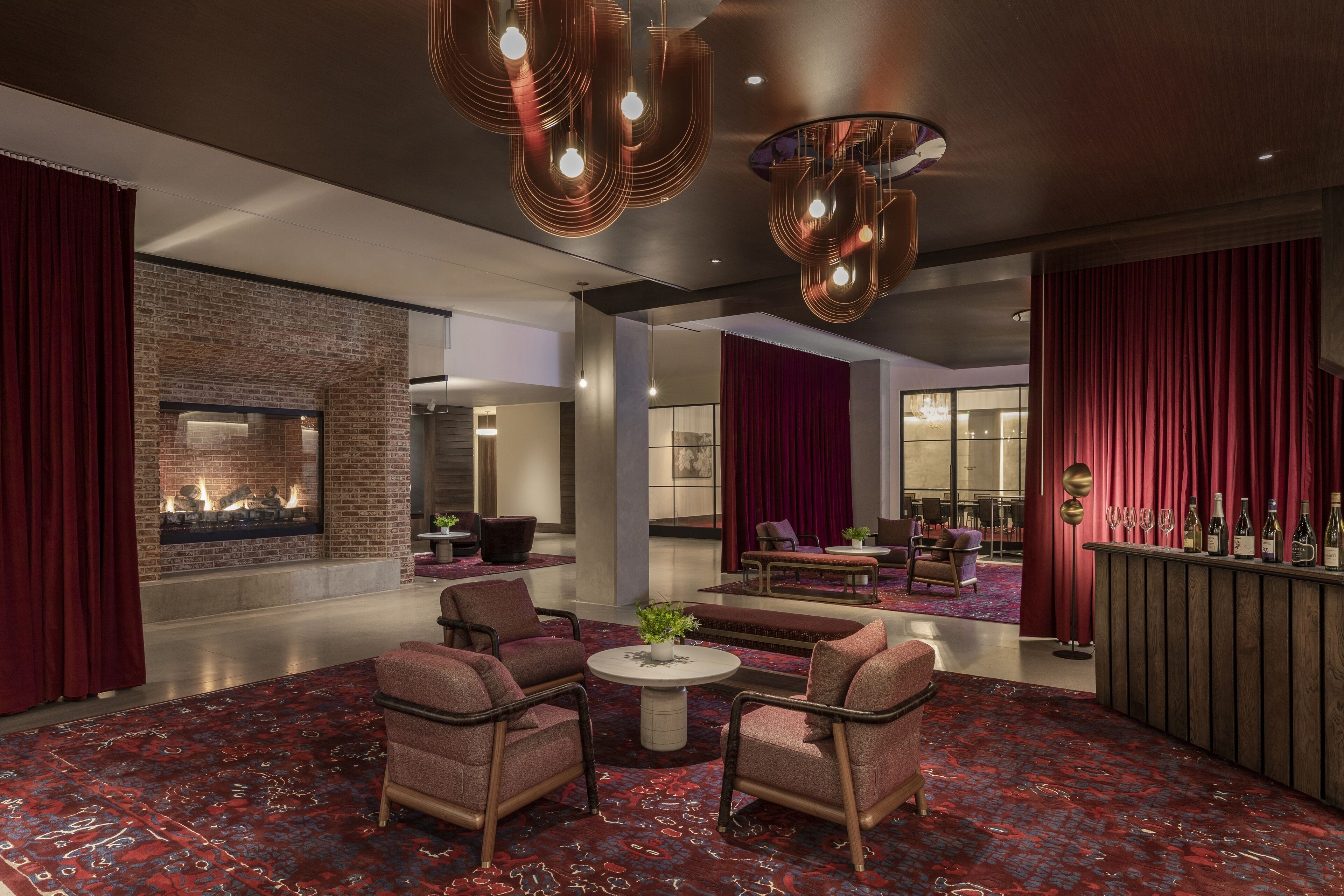 A modern lobby with a fireplace, seating area, and a bar.