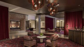 A modern lobby with a fireplace, seating area, and a bar.