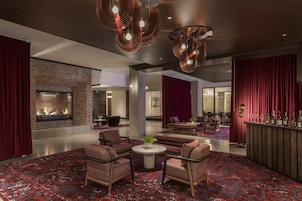 A modern lobby with a fireplace, seating area, and a bar.