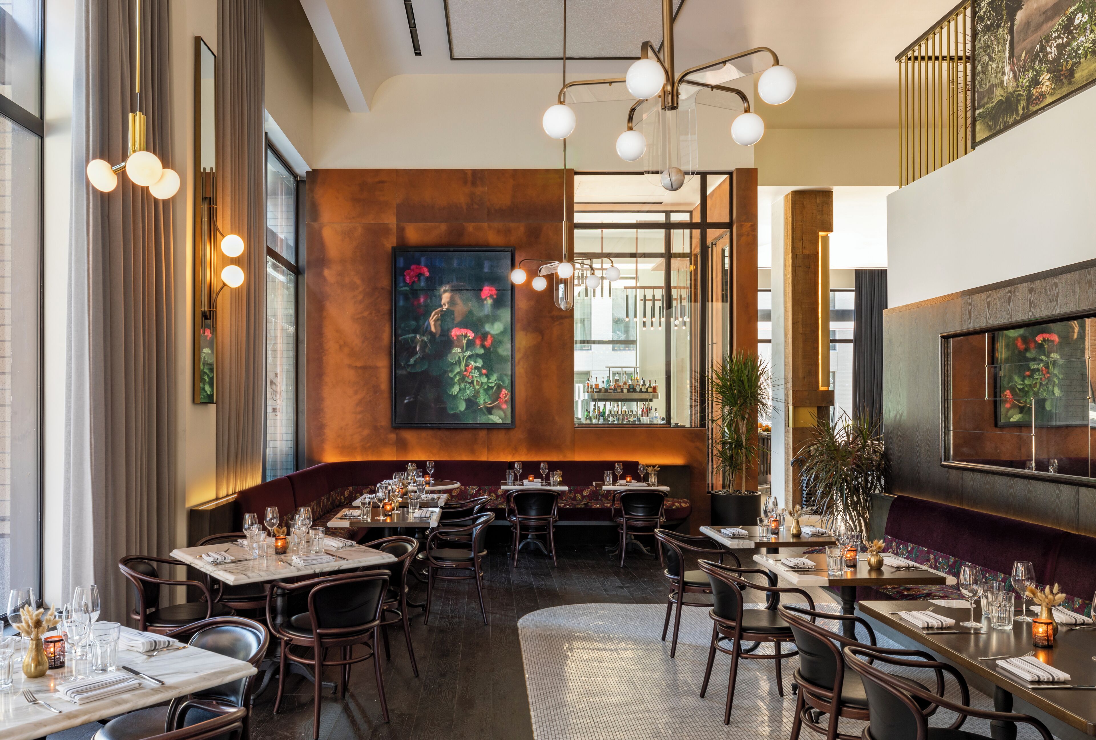 A restaurant with multiple dining tables, chairs, and a large painting on the wall.