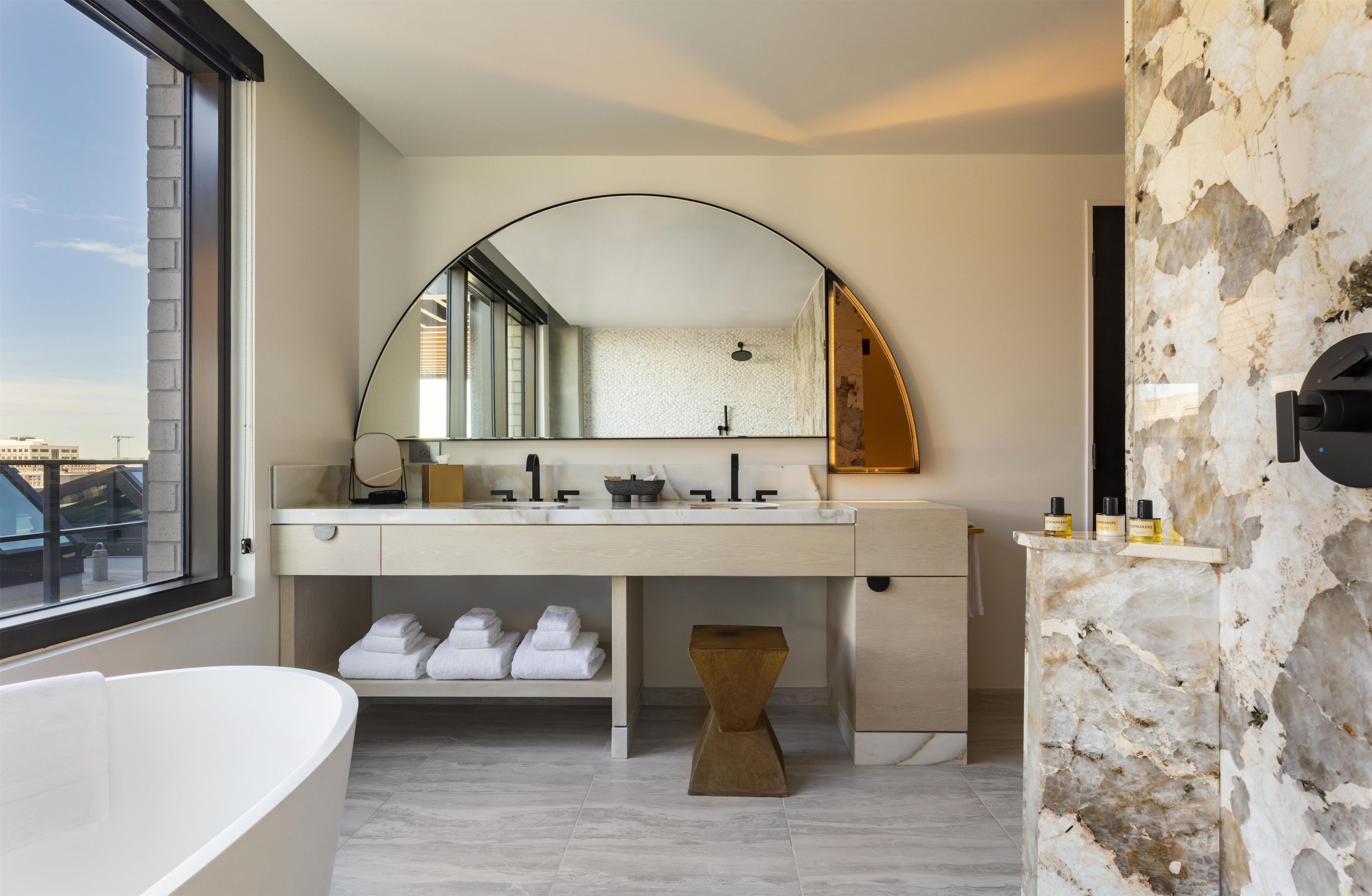 A modern bathroom with a freestanding bathtub, a large mirror, and a vanity with a marble countertop.
