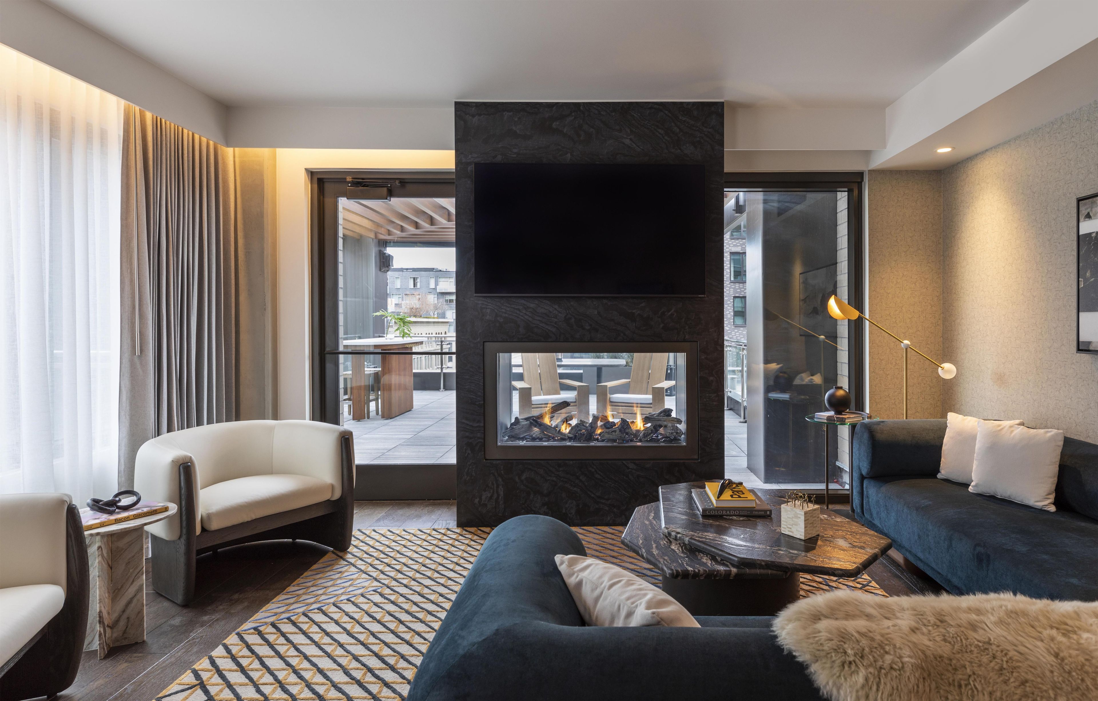 Un salon moderne avec une cheminée, un canapé, un fauteuil et une table basse.