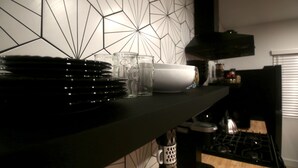 A kitchen counter with stacked plates, glasses, and a white bowl. - 2BR Lit & Spacious Across from Netflix (Los Angeles)