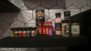 A variety of spice bottles and jars on a shelf against a geometric-patterned wall. - 2BR Lit & Spacious Across from Netflix (Los Angeles)