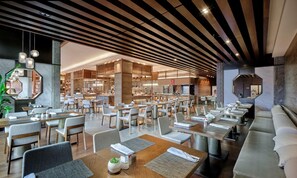 A modern restaurant with a long dining area, multiple tables, and a central kitchen. - Hualuxe Suzhou Bay Hot Spring Resort, an IHG Hotel (Suzhou)