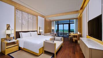 A hotel room with a large bed, a sofa, a TV, and a view of the outdoors.