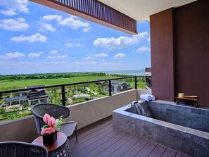 A balcony with a view of a green landscape, a hot tub, and wicker furniture. - Hualuxe Suzhou Bay Hot Spring Resort, an IHG Hotel (Suzhou)