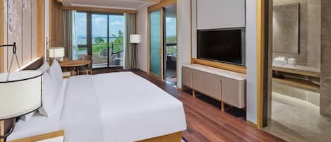 Una habitación de hotel con cama, televisor, escritorio y balcón con vistas.