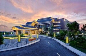 A modern hotel with a curved driveway, a well-maintained garden, and a clear sky. - Hualuxe Suzhou Bay Hot Spring Resort, an IHG Hotel (Suzhou)