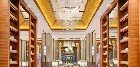 A hotel lobby with wooden shelving, a central chandelier, and a reception desk. - Hualuxe Suzhou Bay Hot Spring Resort, an IHG Hotel (Suzhou)