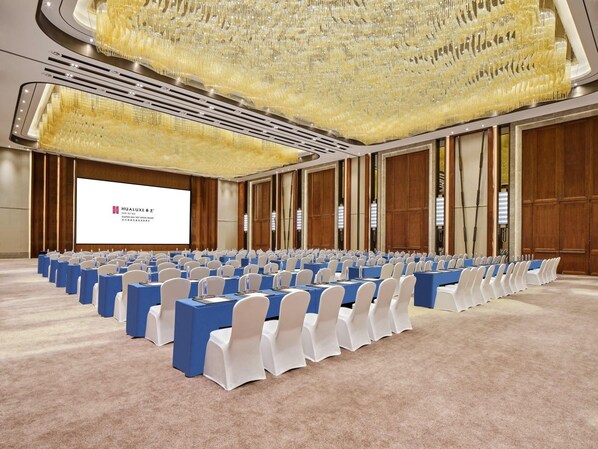 A conference room with rows of tables and chairs, a large screen, and a decorative ceiling. - Hualuxe Suzhou Bay Hot Spring Resort, an IHG Hotel (Suzhou)