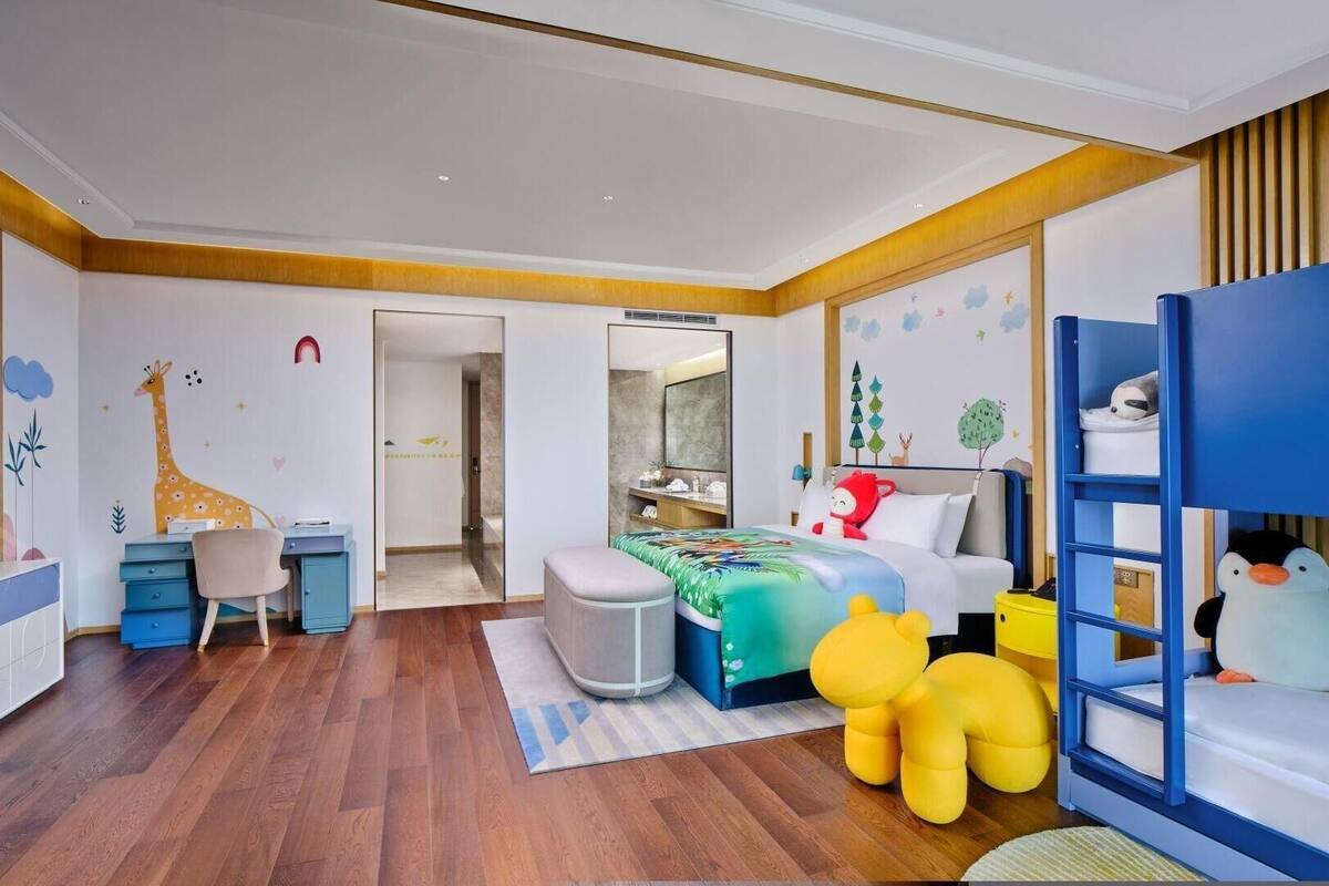 A child's bedroom with a bunk bed, desk, chair, and playful wall decorations.