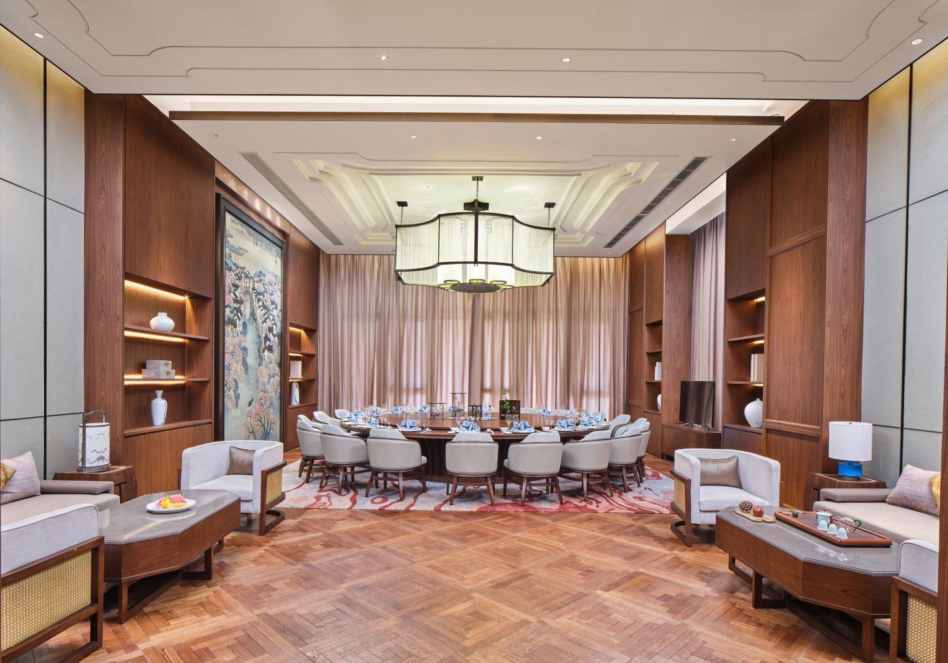 A conference room with a round table, chairs, and a chandelier.