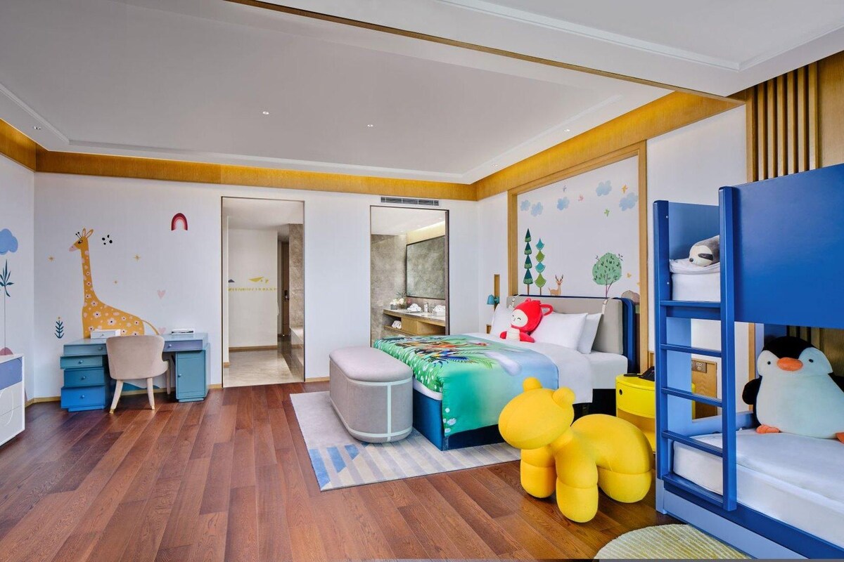 A child's bedroom with a bunk bed, desk, chair, and playful wall decorations.