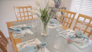 A dining table set with plates, glasses, and a vase of white flowers. - 3828 The 9th Green - Near Golf Links & Bay Trail (Pacific Grove)