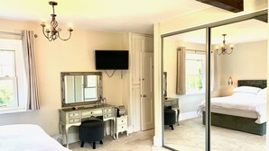 A bedroom with a large mirror, a vanity, a bed, and a sliding door leading to another room. - The Estate - 11 Bed - Sleeps 22 - Private Garden (Hailsham)