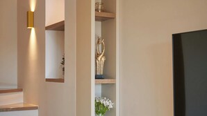 A modern interior with a staircase, built-in shelves, a flat-screen TV, and decorative items. - Apartment Blù (Dubrovnik)