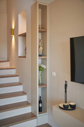 Una escalera con un estante empotrado, una lámpara de pared y un televisor de pantalla plana.