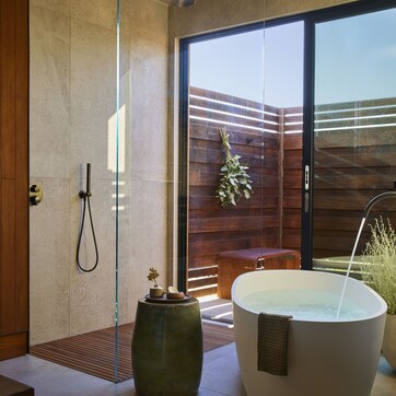 A modern bathroom with a glass-enclosed shower, a freestanding bathtub, and a wooden bench.