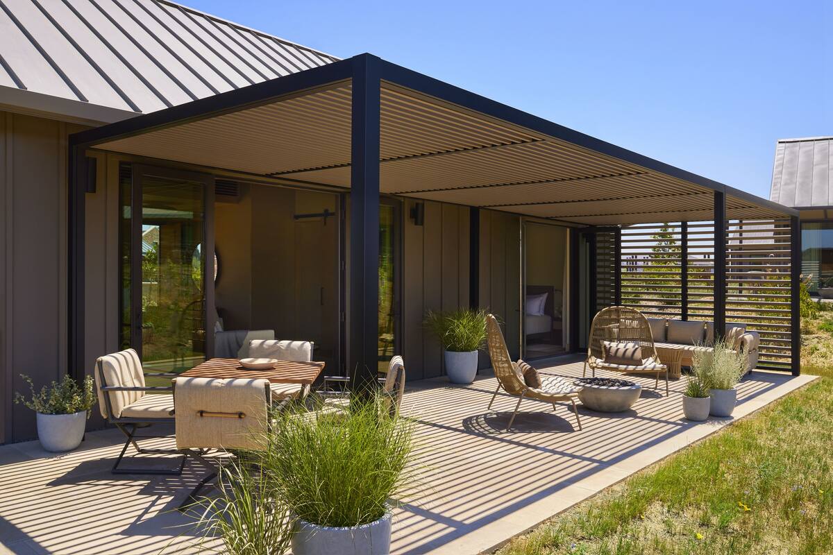 An outdoor patio with a covered seating area, potted plants, and a modern architectural design.