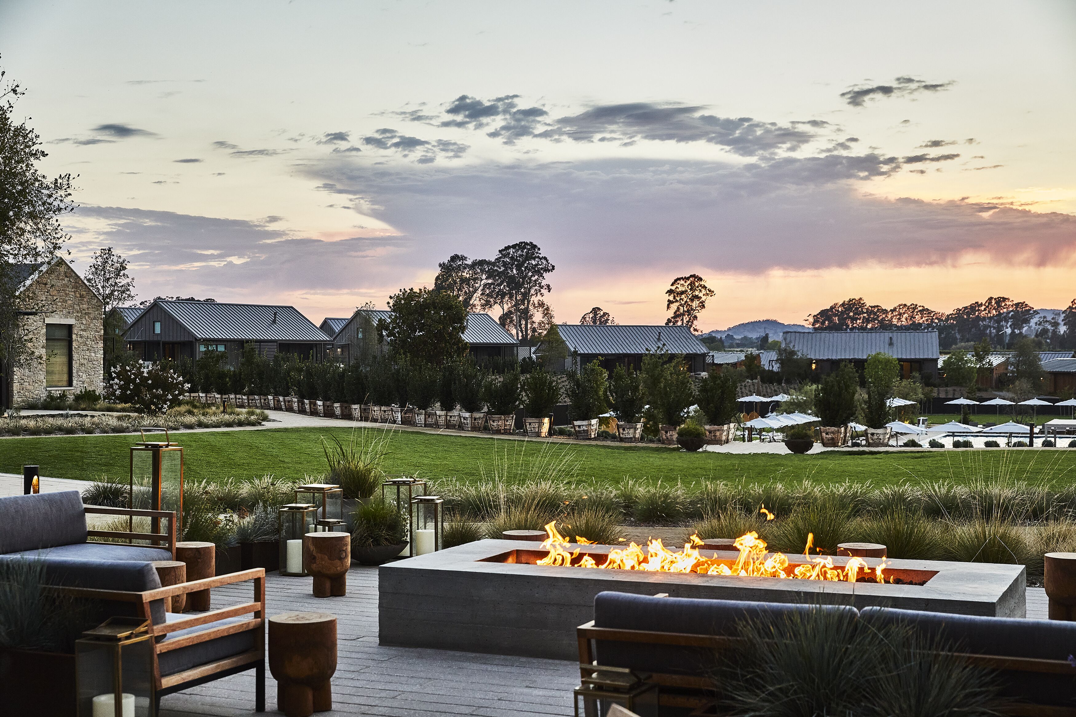 A patio area with a fire feature, outdoor seating, and a view of the surrounding landscape and buildings.